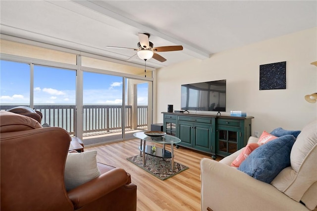 living area with beamed ceiling, light wood-type flooring, and ceiling fan