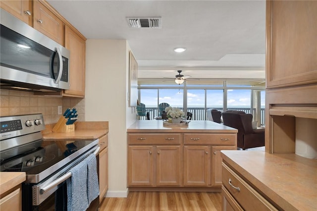 kitchen with light wood finished floors, visible vents, backsplash, light countertops, and appliances with stainless steel finishes