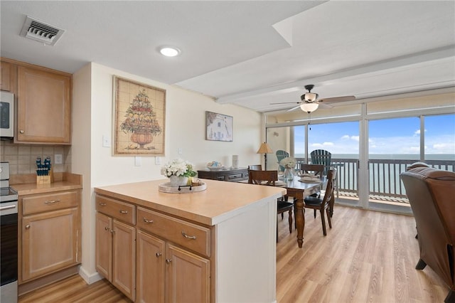 kitchen featuring visible vents, light wood-style flooring, backsplash, light countertops, and white microwave