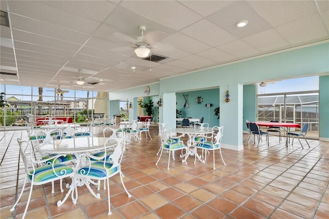 view of patio / terrace with glass enclosure, outdoor dining area, visible vents, and ceiling fan