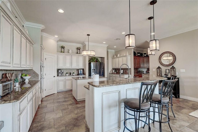 kitchen with backsplash, stainless steel fridge, pendant lighting, a center island with sink, and ornamental molding