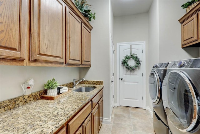 laundry area with washing machine and clothes dryer, sink, light tile patterned floors, and cabinets