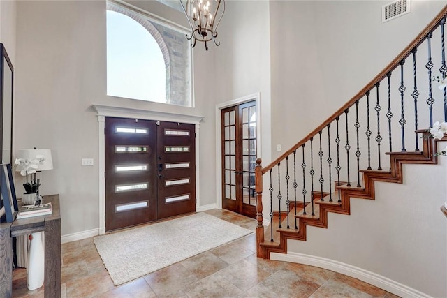 foyer with french doors, a towering ceiling, and an inviting chandelier