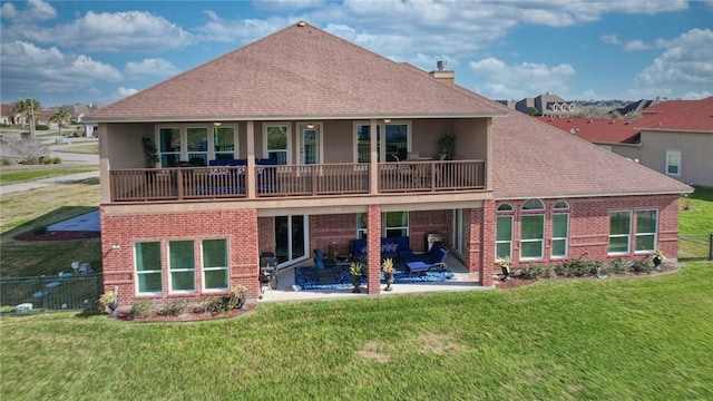 back of property featuring a balcony, a patio area, and a lawn