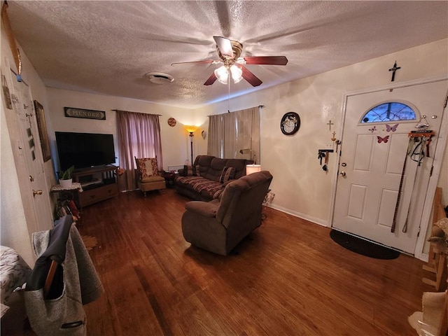 living room with ceiling fan, dark wood-type flooring, and a textured ceiling