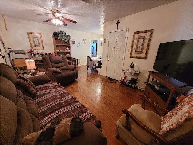 living room featuring ceiling fan, hardwood / wood-style floors, and a textured ceiling