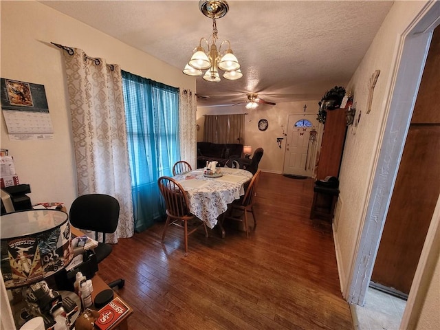 dining area featuring dark wood-type flooring, ceiling fan with notable chandelier, and a textured ceiling