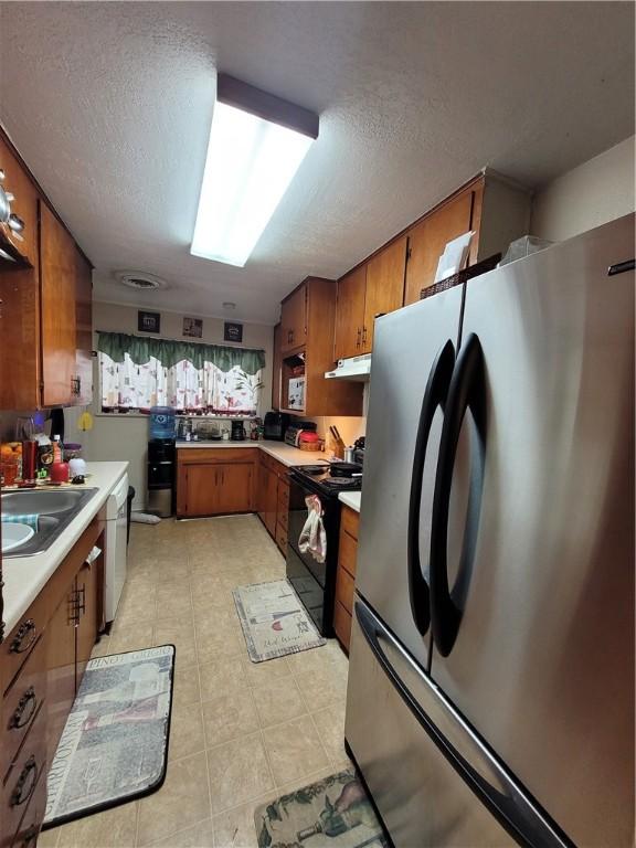 kitchen with dishwasher, sink, stainless steel fridge, black range with electric cooktop, and a textured ceiling