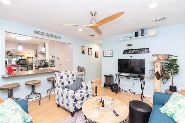 living room featuring light hardwood / wood-style flooring and ceiling fan