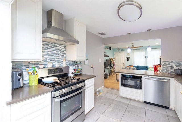 kitchen featuring white cabinetry, wall chimney range hood, light tile patterned floors, and stainless steel appliances