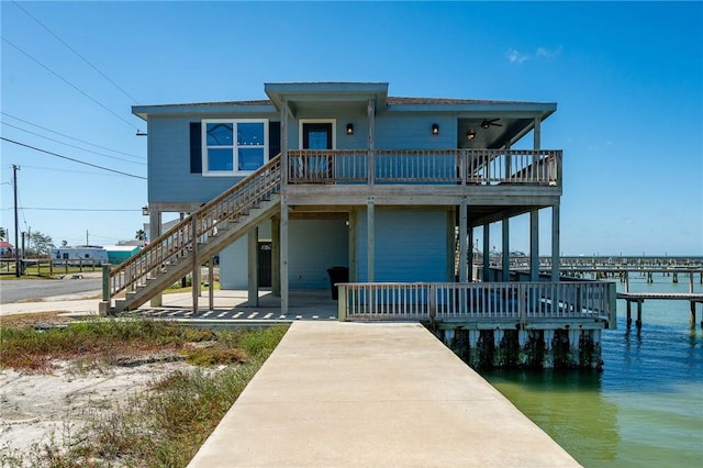 view of front of property featuring a ceiling fan, a water view, and stairway