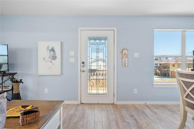 doorway to outside with light wood finished floors and baseboards