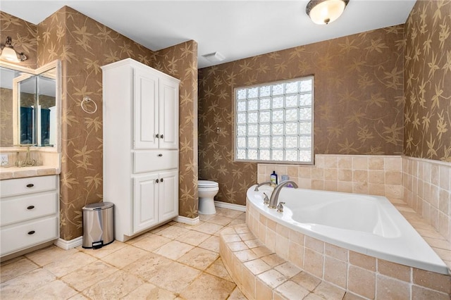 bathroom with a garden tub, baseboards, wallpapered walls, and toilet