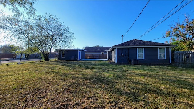 rear view of property with a shed, central AC unit, and a lawn