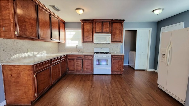 kitchen featuring dark hardwood / wood-style floors, decorative backsplash, white appliances, and sink