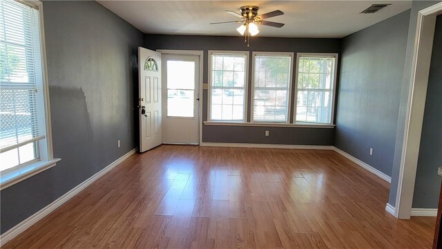 empty room with a wealth of natural light, ceiling fan, and light wood-type flooring