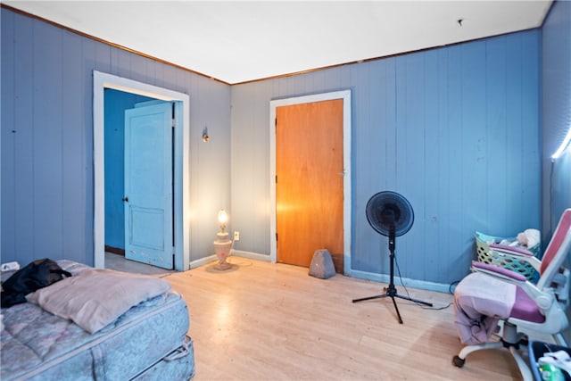 bedroom with wooden walls and light wood-type flooring