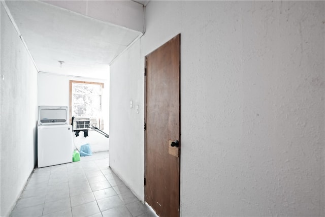 corridor with light tile patterned floors and washer / dryer