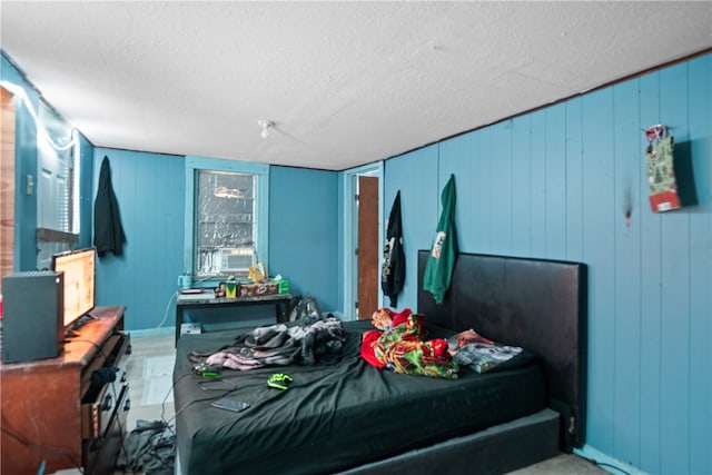 bedroom with wooden walls and a textured ceiling