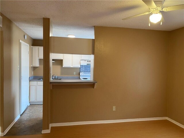 kitchen with white cabinetry, ceiling fan, and a textured ceiling