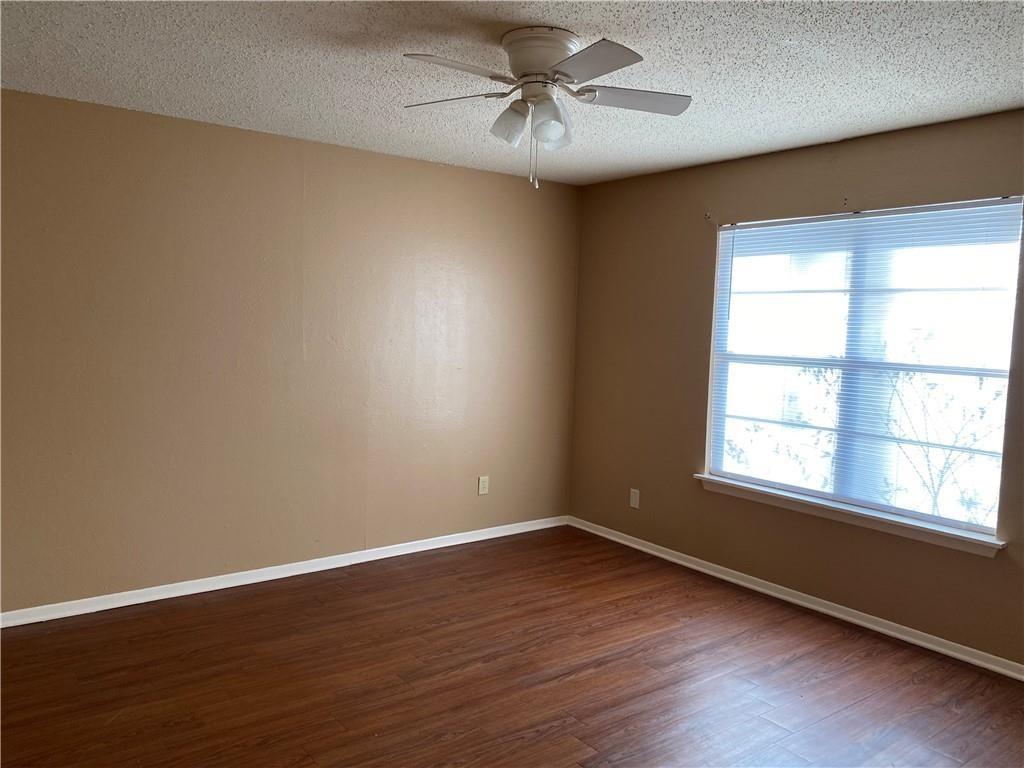 empty room featuring dark wood-type flooring, ceiling fan, and a textured ceiling