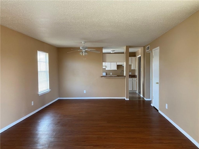 unfurnished living room featuring dark hardwood / wood-style floors, a textured ceiling, and ceiling fan