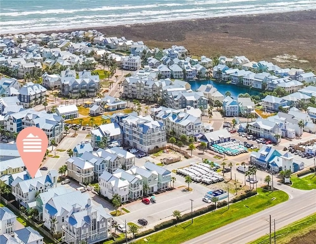 drone / aerial view featuring a water view, a residential view, and a beach view