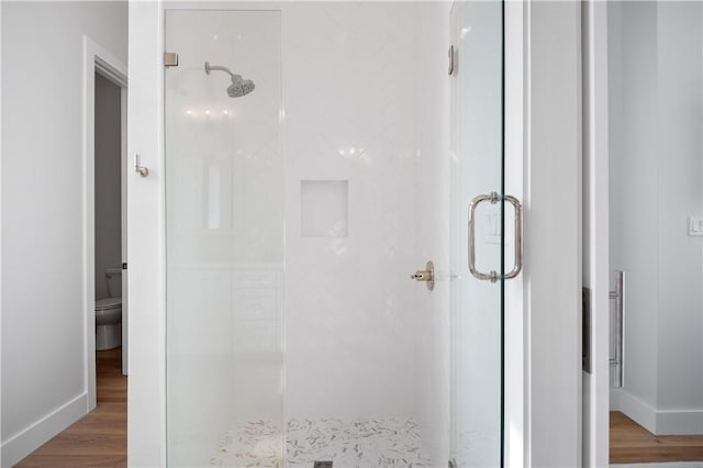 bathroom featuring a stall shower, baseboards, and wood finished floors