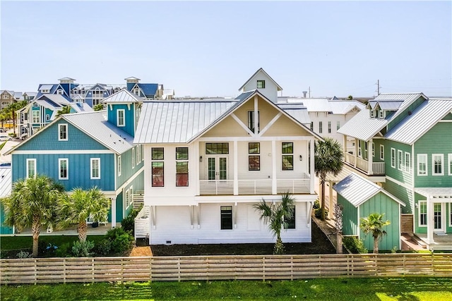 rear view of property featuring a residential view, a standing seam roof, metal roof, and fence