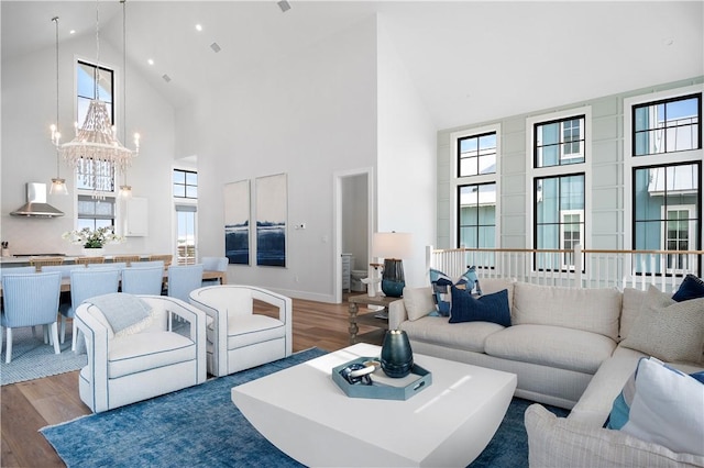 living room with a notable chandelier, baseboards, wood finished floors, and a healthy amount of sunlight