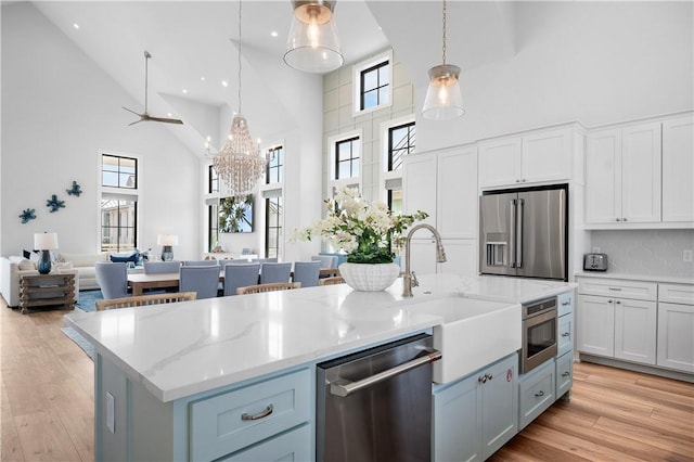 kitchen featuring light wood finished floors, an island with sink, open floor plan, stainless steel appliances, and a sink