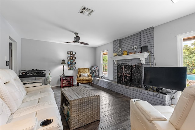 living room with a fireplace, dark wood-type flooring, a healthy amount of sunlight, and ceiling fan