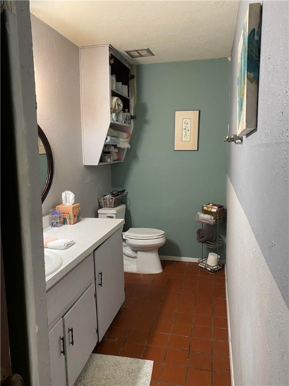 bathroom with tile patterned flooring, vanity, a textured ceiling, and toilet