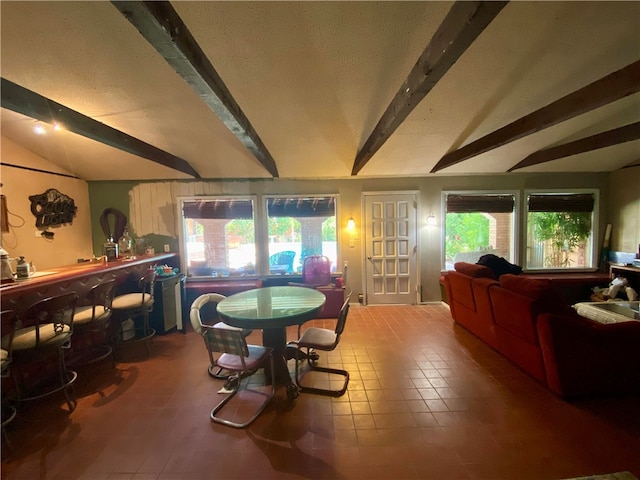 dining space with vaulted ceiling with beams and indoor bar