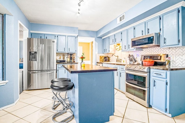 kitchen with stainless steel appliances, a kitchen island, and blue cabinets