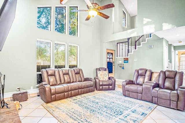 tiled living room with ceiling fan and a high ceiling