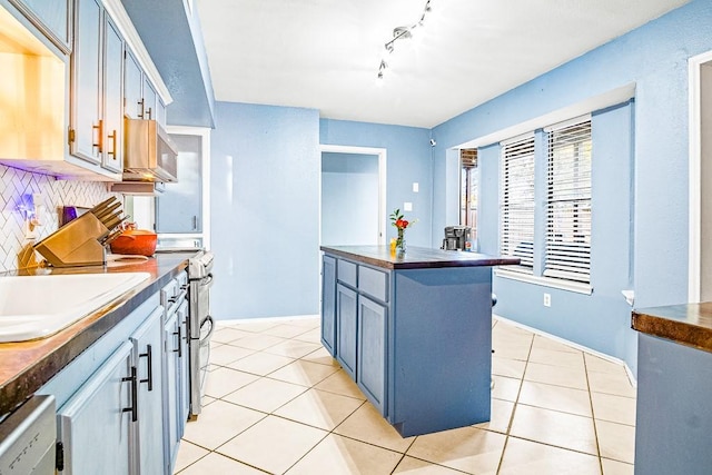 kitchen with track lighting, a kitchen island, decorative backsplash, blue cabinetry, and light tile patterned floors