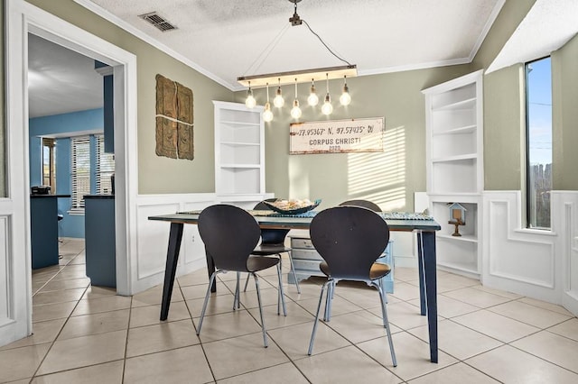 dining space featuring a textured ceiling, ornamental molding, and light tile patterned flooring