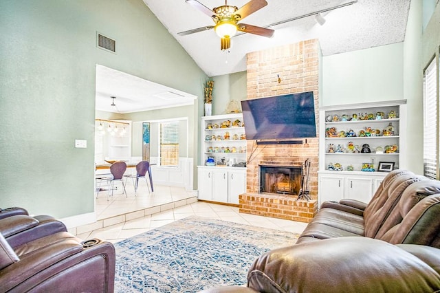 living room with a textured ceiling, a fireplace, light tile patterned floors, high vaulted ceiling, and ceiling fan