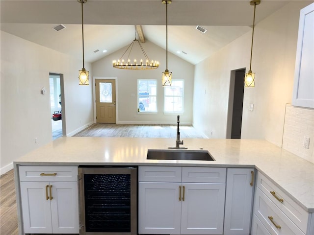 kitchen with wine cooler, sink, pendant lighting, and white cabinetry