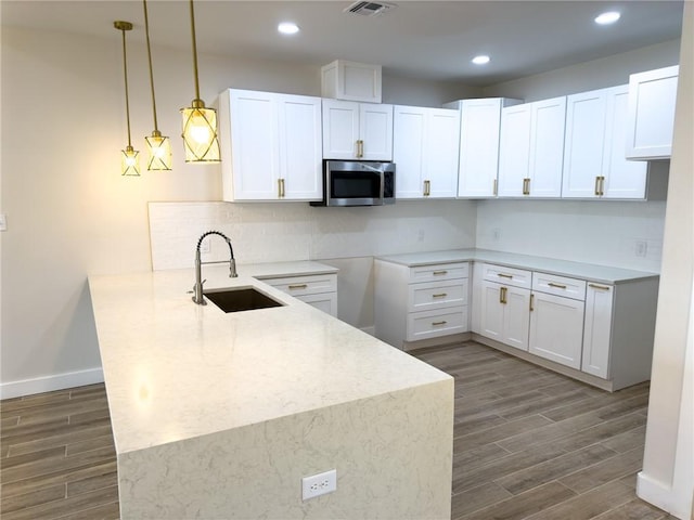 kitchen featuring tasteful backsplash, sink, white cabinets, hanging light fixtures, and kitchen peninsula