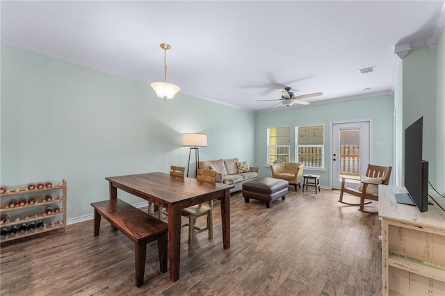 dining space with baseboards, visible vents, a ceiling fan, wood finished floors, and crown molding