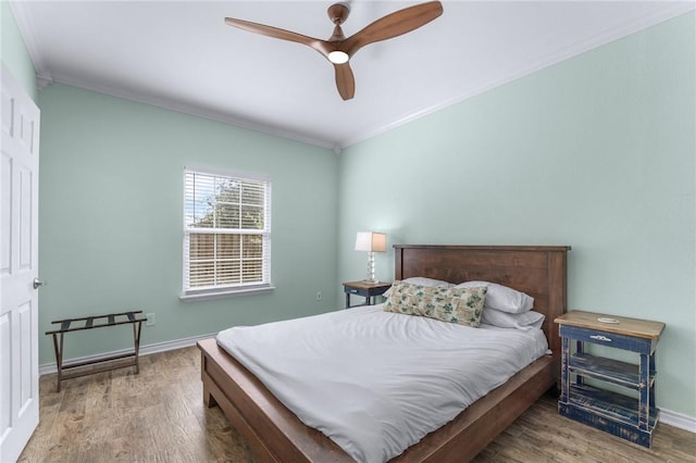 bedroom with baseboards, ceiling fan, wood finished floors, and crown molding