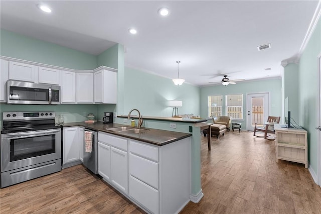 kitchen featuring a peninsula, a sink, visible vents, appliances with stainless steel finishes, and dark countertops