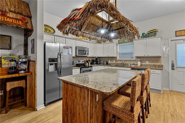 kitchen featuring light wood-type flooring, white cabinetry, a center island, and stainless steel appliances