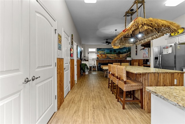 kitchen featuring white cabinetry, ceiling fan, stainless steel fridge, and light hardwood / wood-style flooring