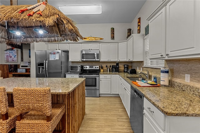 kitchen with stainless steel appliances, white cabinetry, light stone countertops, sink, and light hardwood / wood-style flooring