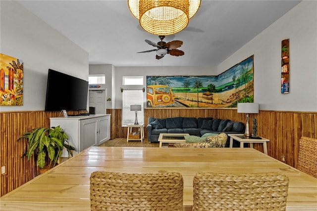 dining room featuring hardwood / wood-style flooring, ceiling fan, and wooden walls