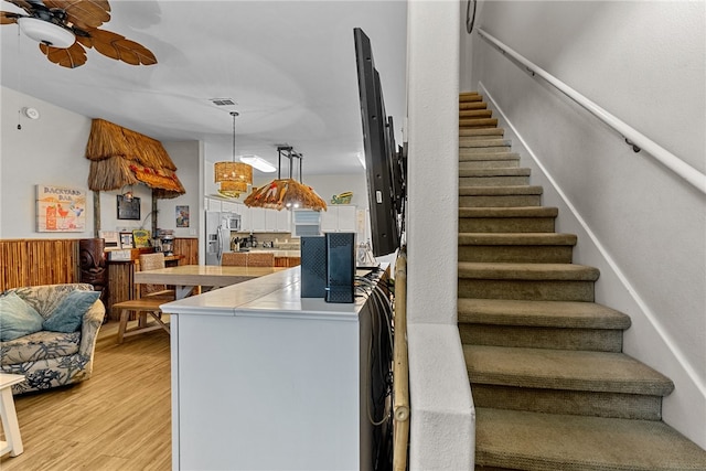 kitchen featuring ceiling fan with notable chandelier, stainless steel appliances, pendant lighting, white cabinetry, and light hardwood / wood-style flooring