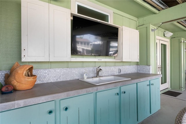 kitchen with blue cabinets, decorative backsplash, and a sink